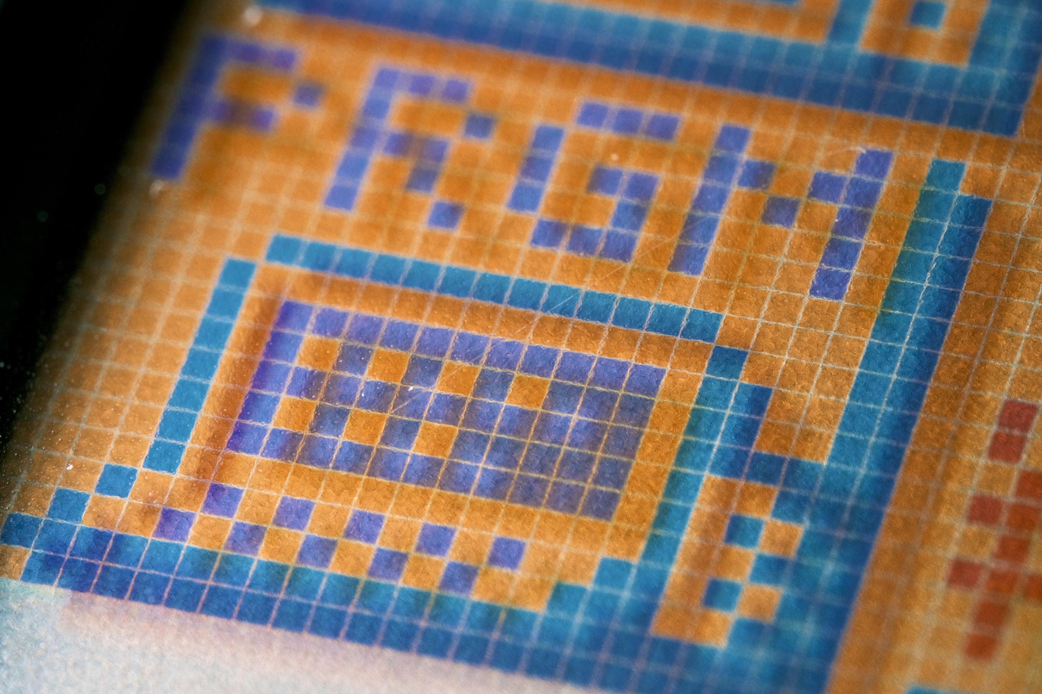 A closeup of a very pixelated computer titled PRGM. The computer, while clearly detectable as one is heavily stylised and somewhat retro. More a terminal than a modern computer. It is made of marine blue and dark cyan pixels, with dark orange pixels being the background colour