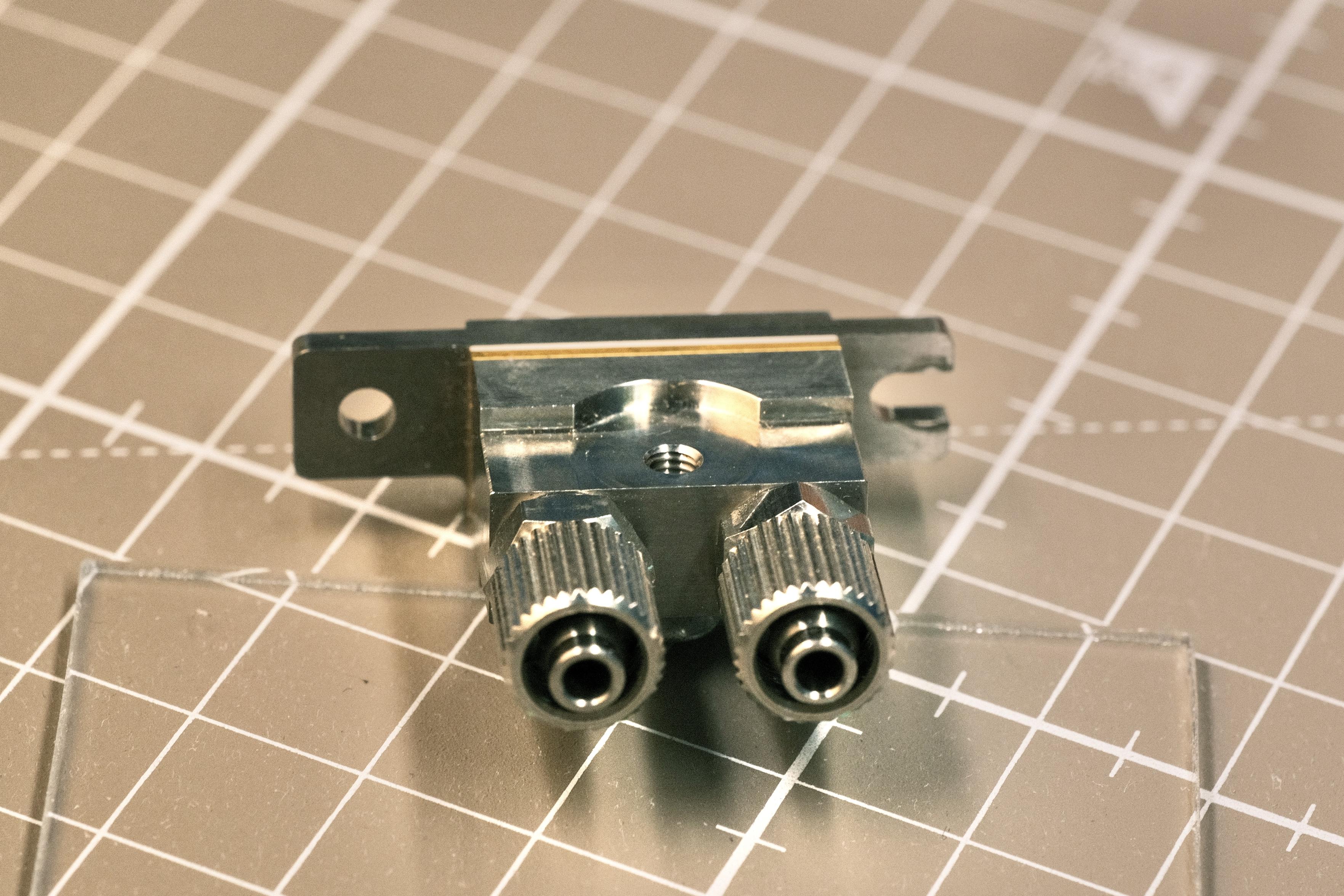 Photo of the back of the case. It rests on a glass slide and the mat. Two outlets that look like luer lock hint at this device consuming a lot of power, it’s a water cooling circuit